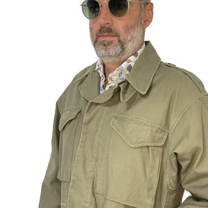 May include: A green military-style jacket with a zipper closure and multiple pockets. The jacket has a relaxed fit and is made of a durable fabric.
