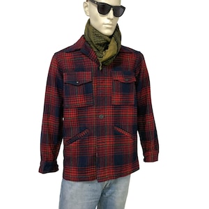 May include: A red and navy plaid jacket with four front pockets and a button closure. The jacket is worn over a green scarf and light blue jeans. The mannequin is wearing black sunglasses.