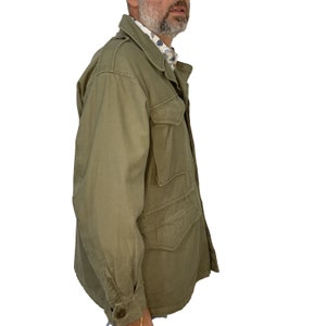 May include: A green field jacket with a button-up front and multiple pockets. The jacket is made of a durable cotton fabric.