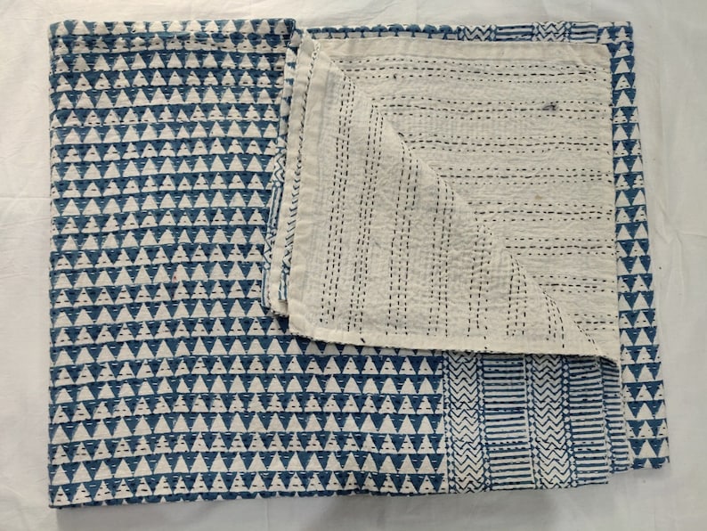 May include: A blue and white kantha quilt with a geometric pattern. The quilt is made of cotton and is hand-stitched. It is a traditional Indian textile.