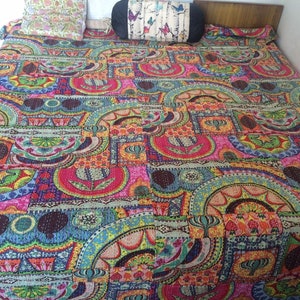 May include: A colorful kantha quilt with a patchwork design featuring various geometric shapes and floral patterns in shades of pink, blue, green, yellow, and brown.