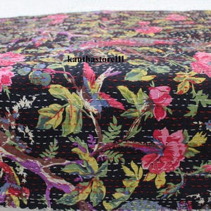 May include: Black kantha quilt with a floral pattern featuring pink, red, and green flowers, leaves, and birds. The quilt is hand-stitched with a running stitch and has a black background.