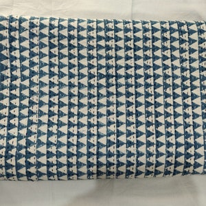 May include: A blue and white fabric with a repeating pattern of triangles. The fabric is folded in half and has a rough texture.