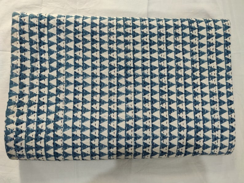 May include: A blue and white fabric with a repeating pattern of triangles. The fabric is folded in half and has a rough texture.