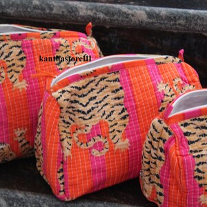 May include: Three zippered pouches with a tiger print design. The pouches are made of a quilted fabric with orange and pink stripes. The pouches are lined with white fabric.