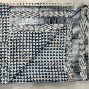 May include: A blue and white kantha quilt with a geometric pattern. The quilt is folded in half and has a textured surface.