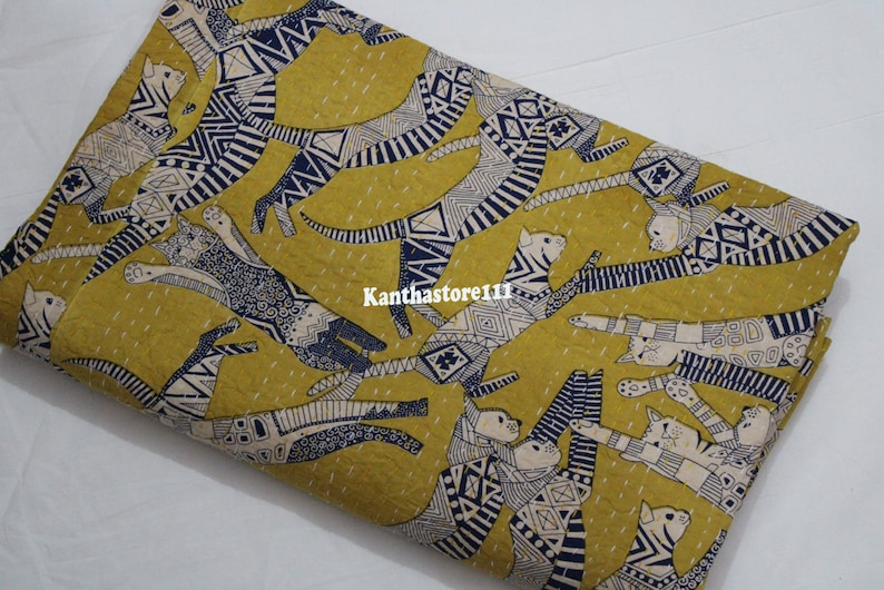 May include: Yellow fabric with a repeating pattern of stylized cats in black and white with blue accents. The fabric has a subtle texture and is perfect for quilting or crafting.