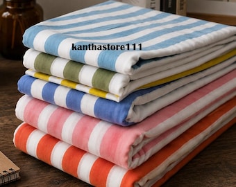 May include: A stack of folded fabric pieces featuring vertical stripes in various colors including light blue, olive green, yellow, medium blue, pink, and orange, all alternating with white. The text kanthastore111 is visible on the top layer.