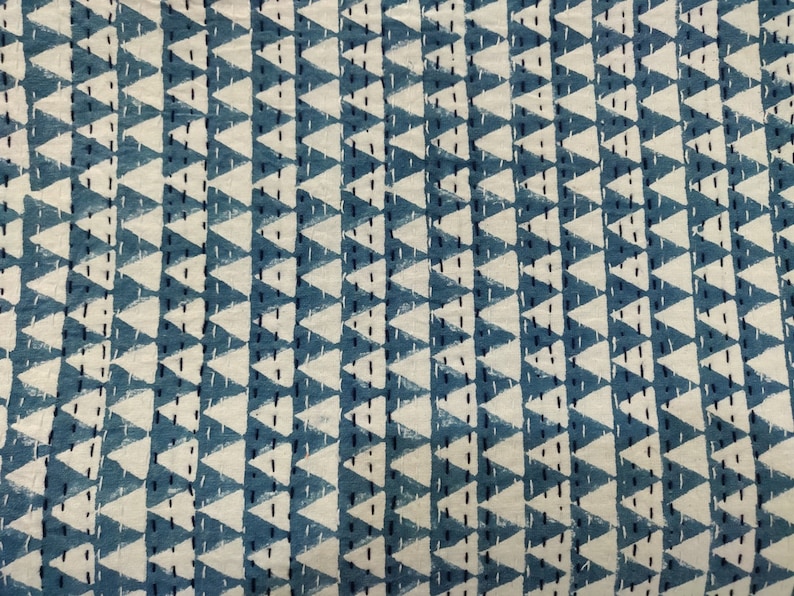 May include: A blue and white fabric with a repeating pattern of white triangles on a blue background. The triangles are outlined in black and have a textured look.