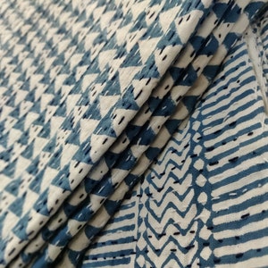 May include: Close-up of a blue and white fabric with a geometric pattern. The fabric is folded in thirds, showing the pattern on both sides.