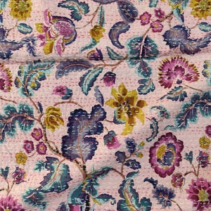 Op de afbeelding: Roze kantha-deken met een bloemenpatroon in tinten paars, geel en blauw. De deken is gemaakt van katoen en heeft een handgestikt ontwerp.