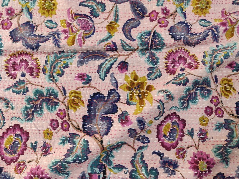 Op de afbeelding: Roze kantha-deken met een bloemenpatroon in tinten paars, geel en blauw. De deken is gemaakt van katoen en heeft een handgestikt ontwerp.