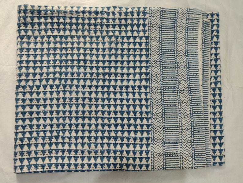 May include: A blue and white kantha quilt with a geometric pattern. The quilt is made of cotton and is hand-stitched. It is a traditional Indian textile.