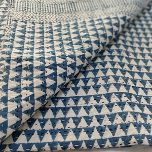 May include: A white cotton quilt with a blue triangle pattern. The quilt is folded in half and the pattern is visible on both sides.