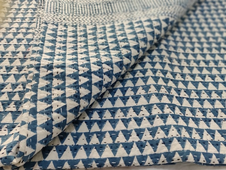 May include: A white cotton quilt with a blue triangle pattern. The quilt is folded in half and the pattern is visible on both sides.