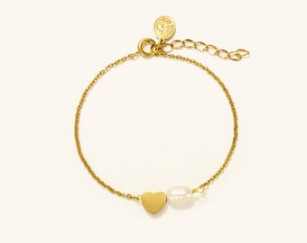 May include: A gold-colored bracelet with a heart charm and a white pearl. The bracelet has a delicate chain design and an adjustable clasp. The heart charm is solid and smooth. The pearl is oval-shaped.