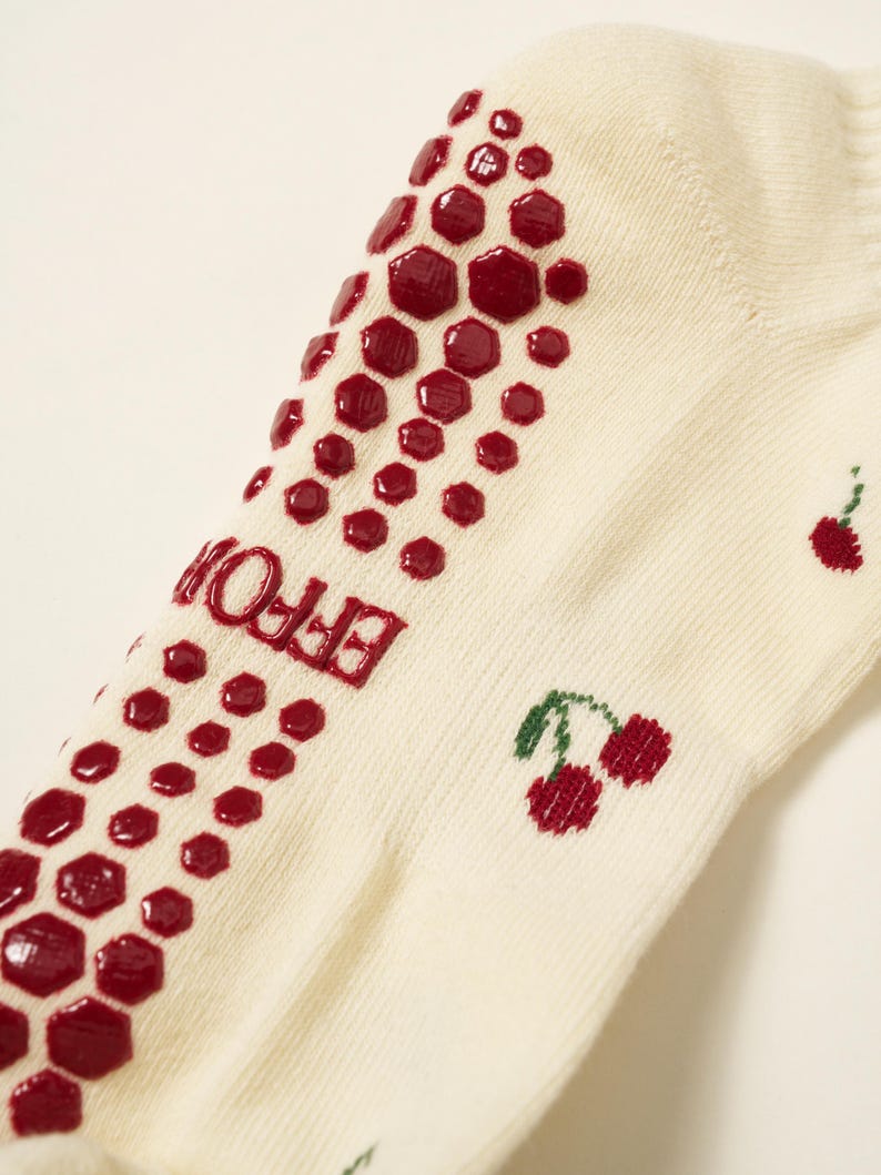 Peut inclure: Chaussettes cr&egrave;me avec un motif antid&eacute;rapant hexagonal rouge et des cerises brod&eacute;es. Le mot "EFFOR" est imprim&eacute; en rouge sur le c&ocirc;t&eacute;. Les chaussettes sont en mati&egrave;re douce et confortable.
