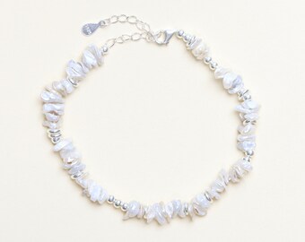 May include: A delicate silver chain bracelet with a cluster of white irregular shaped pearls. The bracelet has a lobster clasp closure.