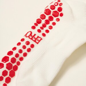 May include: White ankle sock with red hexagonal grip pattern on the sole. The word "EFFO" is printed in red on the side of the sock. The sock is made of a soft, ribbed fabric.