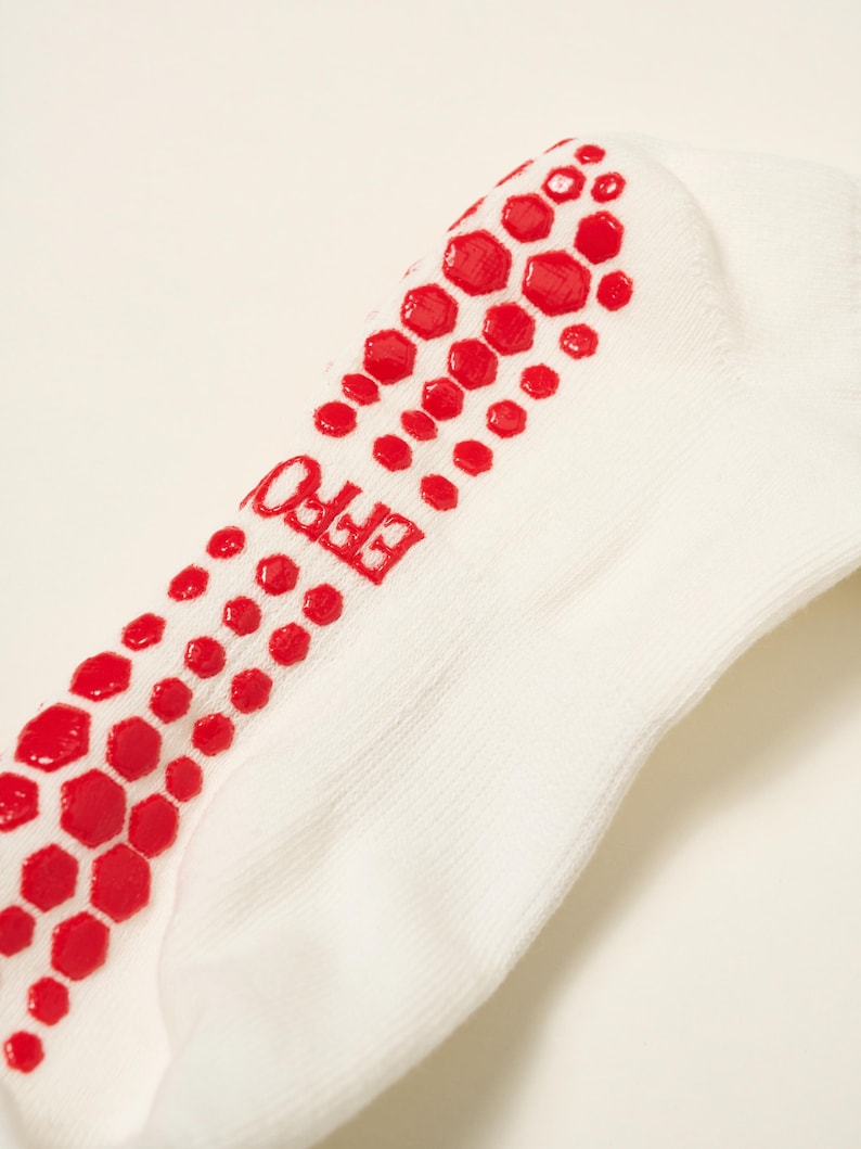 May include: White ankle sock with red hexagonal grip pattern on the sole. The word "EFFO" is printed in red on the side of the sock. The sock is made of a soft, ribbed fabric.