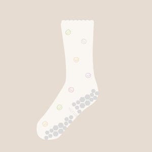 May include: A white sock with a scalloped top edge and a pattern of colorful smiley faces. The sole features a gray, honeycomb-patterned grip. The sock is designed for comfort and style.