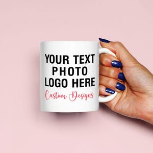 Può includere: Una tazza in ceramica bianca con testo nero che recita "YOUR TEXT PHOTO LOGO HERE" e testo rosa che recita "Custom Designs".