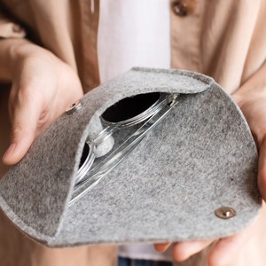 May include: A gray felt sunglasses case with a zipper closure. The case is open and a pair of sunglasses is inside.