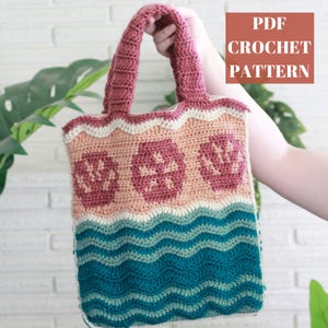 May include: A handmade crochet tote bag with a floral design and wavy stripes in shades of pink, peach, teal, and cream. The bag has a rectangular shape with a sturdy handle. The text "PDF CROCHET PATTERN" is displayed in a red square.