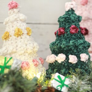 Puede incluir: Dos &aacute;rboles de Navidad de crochet decorados con flores de terciopelo. El &aacute;rbol de la izquierda es blanco con flores amarillas y rosas. El &aacute;rbol de la derecha es verde con flores rosas y burdeos.