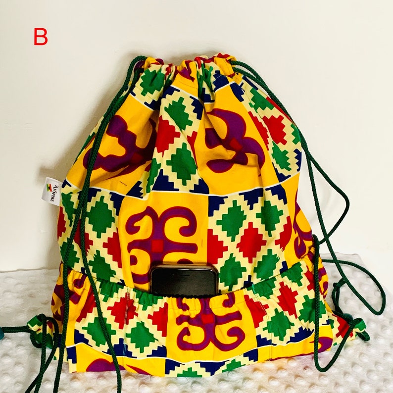 May include: A yellow, green, red, and purple drawstring bag with a geometric pattern and a small pocket on the front. The bag has a green drawstring and the text "Africa" is printed on the side.