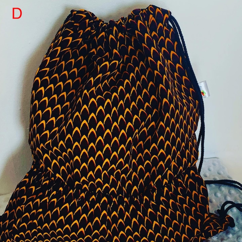 May include: A black and yellow drawstring bag with a geometric pattern. The bag has a single drawstring closure and a single strap.