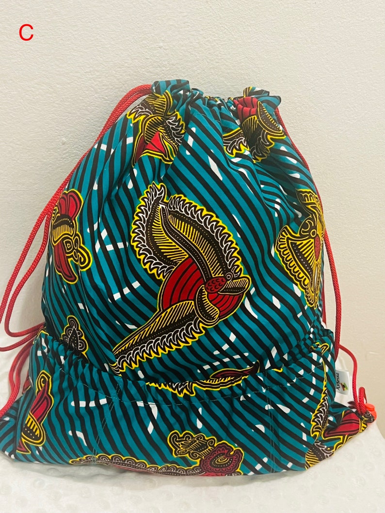 May include: A turquoise drawstring bag with a red and yellow floral pattern. The bag has a red drawstring and a small pocket on the front.