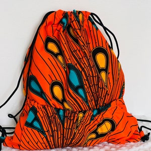 May include: Orange drawstring bag with a black, yellow, and teal African print design.