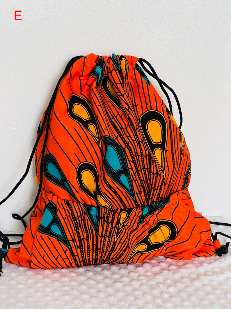 May include: Orange drawstring bag with a black, yellow, and teal African print design.