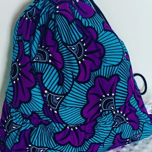 May include: A drawstring bag with a purple and blue floral pattern. The bag has a gathered bottom and a black drawstring.