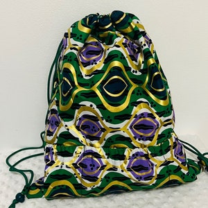 May include: A green, gold, and purple drawstring bag with a geometric pattern. The bag has a small pocket on the front.