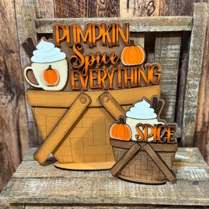 May include: Wooden fall-themed decor featuring two baskets. The larger basket has the words "Pumpkin Spice Everything" and a mug with a pumpkin and whipped cream. The smaller basket has the word "Spice" and a pumpkin.