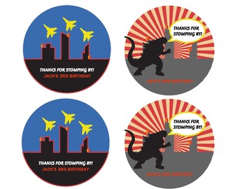 Può includere: Quattro adesivi rotondi a tema Godzilla. Due adesivi presentano una silhouette nera di Godzilla che calpesta una città su uno sfondo di sole rosso e giallo. Gli altri due adesivi presentano uno sfondo blu con una silhouette nera di una città e aerei gialli che volano sopra di essa. Tutti gli adesivi hanno il testo "Grazie per essere venuto! Buon 3° compleanno di Jack!".