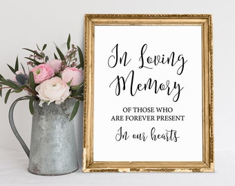 May include: A gold framed sign with the text "In Loving Memory of those who are forever present In our hearts".