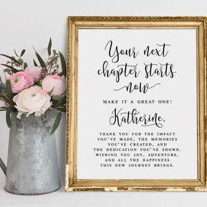 May include: A framed print with gold trim featuring the text "Your next chapter starts now." A bouquet of pink and white flowers sits in a metal pitcher to the left of the frame. The print includes a personalized message.