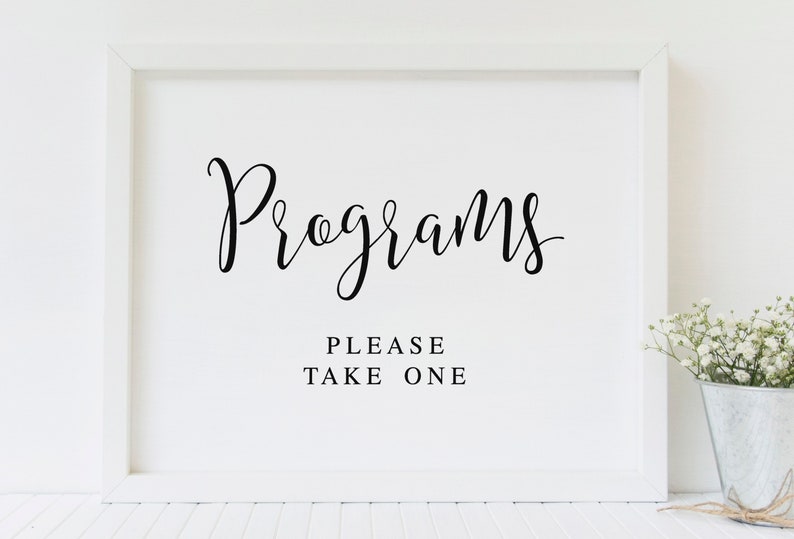 May include: White framed sign with black calligraphy text that reads "Programs" and "Please Take One".