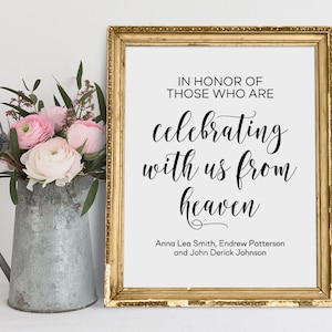 Puede incluir: Un cartel enmarcado con el texto "IN HONOR OF THOSE WHO ARE celebrating with us from heaven" y los nombres "Anna Lea Smith, Endrew Patterson y John Derick Johnson". El cartel está en un marco dorado y está sentado en una mesa con un jarrón de flores rosas.