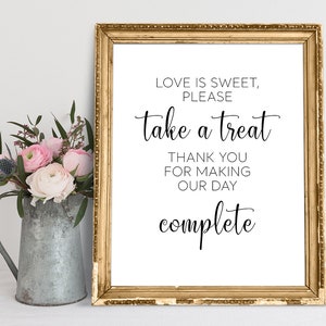 May include: A gold framed sign with the text "LOVE IS SWEET, PLEASE take a treat THANK YOU FOR MAKING OUR DAY complete".