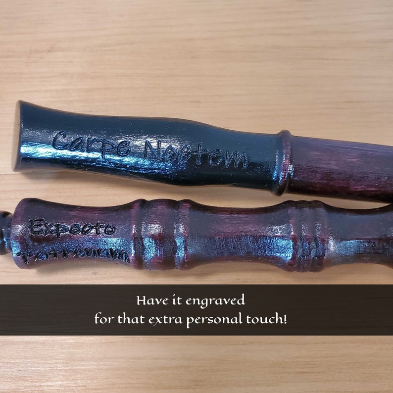 May include: Two wooden wands, one black and one burgundy, with engraved text. The black wand reads "Carpe Noctem," and the burgundy wand reads "Expecto." The image also includes the text "Have it engraved for that extra personal touch!"