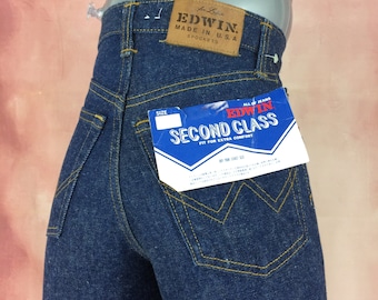 Puede incluir: Vaqueros de mezclilla azul con una etiqueta de cuero marrón que dice "EDWIN. Made in U.S.A. SPOCKETS" y una etiqueta de papel azul y blanca que dice "ALL OF JEANS EDWIN SECOND CLASS FIT FOR EXTRA COMFORT".