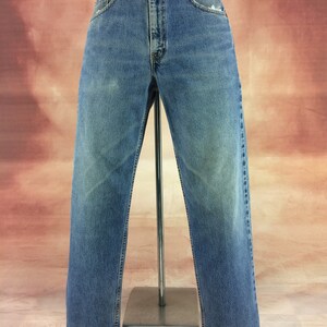 May include: A pair of light blue denim jeans with a straight leg fit. The jeans have a faded look and are distressed at the hem.