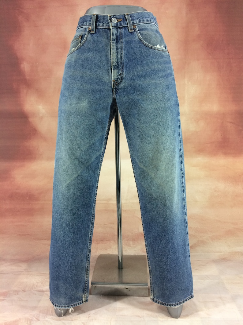May include: A pair of light blue denim jeans with a straight leg fit. The jeans have a faded look and are distressed at the hem.