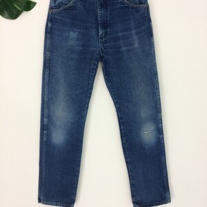 May include: A pair of blue denim jeans with a small hole on the right leg. The jeans have a classic straight leg style and a high waist.
