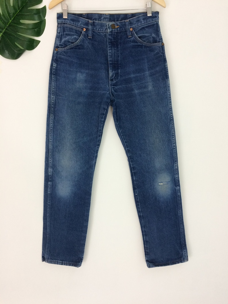 May include: A pair of blue denim jeans with a small hole on the right leg. The jeans have a classic straight leg style and a high waist.