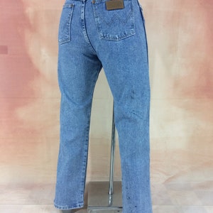 May include: A pair of light blue denim jeans with a brown leather patch on the back pocket that says "Wrangler".